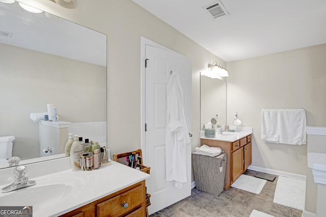 bathroom with two vanities, a sink, and visible vents