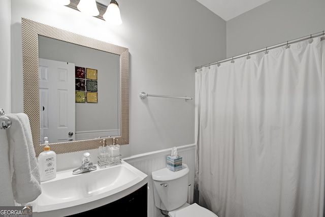 full bath featuring toilet, curtained shower, vanity, and wainscoting