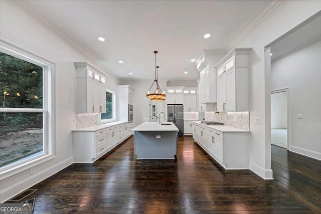 kitchen with hanging light fixtures, tasteful backsplash, a center island with sink, and white cabinetry