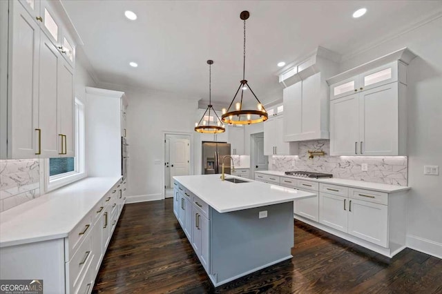 kitchen featuring white cabinetry, a center island with sink, appliances with stainless steel finishes, pendant lighting, and decorative backsplash