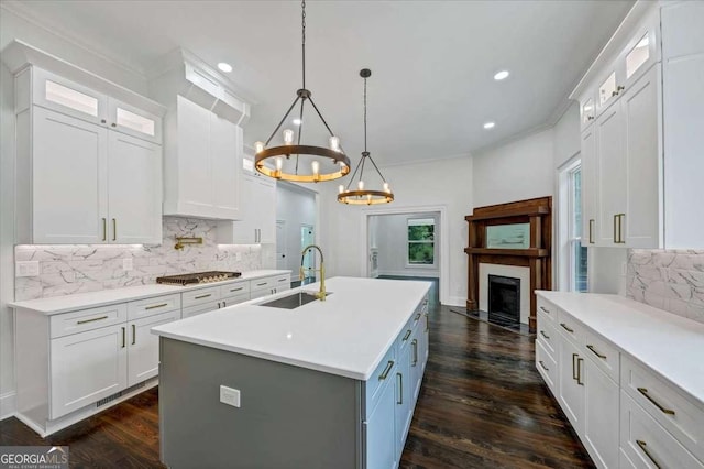 kitchen featuring tasteful backsplash, a kitchen island with sink, sink, and white cabinets