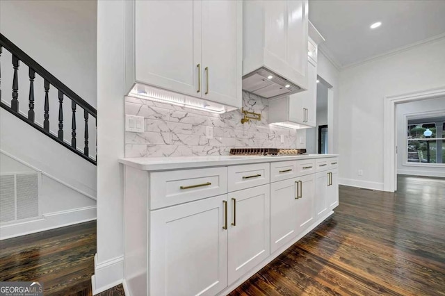 kitchen with tasteful backsplash, dark hardwood / wood-style flooring, ornamental molding, and white cabinets