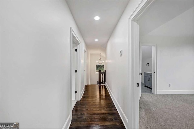 hall featuring a notable chandelier and dark colored carpet