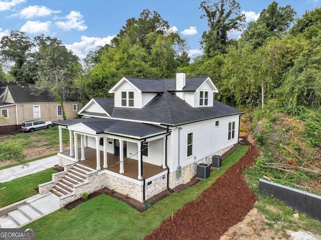 view of front facade with cooling unit, covered porch, and a front lawn