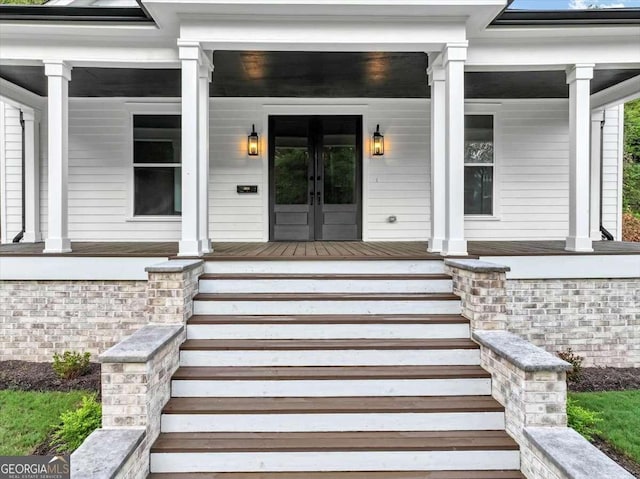 view of exterior entry with french doors and a porch