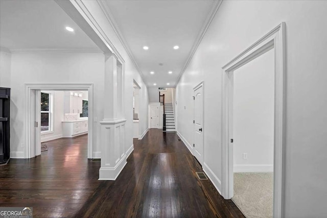 hall with crown molding, dark wood-type flooring, and ornate columns