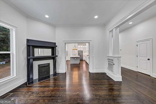 unfurnished living room with ornate columns, crown molding, dark wood-type flooring, and a wealth of natural light