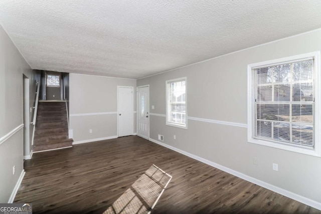 unfurnished room featuring dark hardwood / wood-style floors, a textured ceiling, and a wealth of natural light