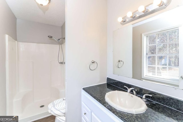 bathroom featuring a shower, vanity, a textured ceiling, and toilet