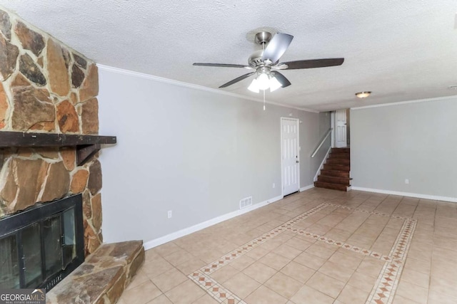 tiled living room featuring ceiling fan, crown molding, a stone fireplace, and a textured ceiling