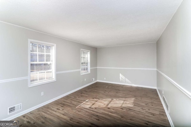 empty room with dark hardwood / wood-style floors and a textured ceiling