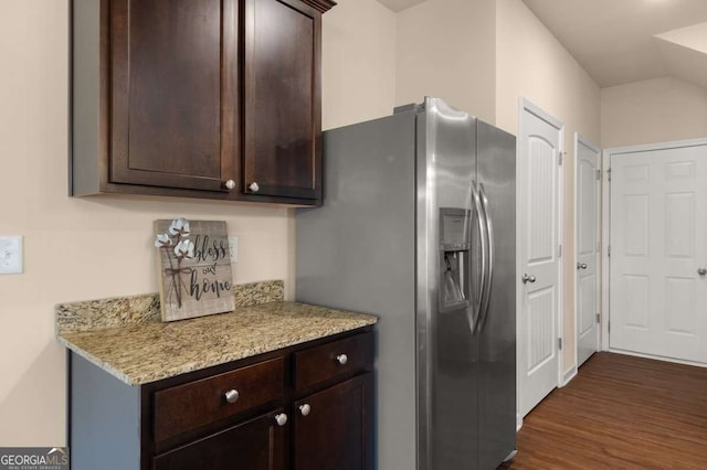 kitchen with light stone counters, dark brown cabinetry, and stainless steel fridge