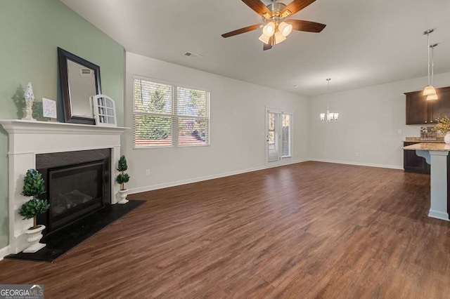 living room featuring a wealth of natural light, dark wood-type flooring, and ceiling fan with notable chandelier