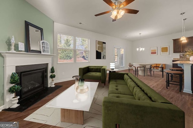 living room with dark wood-type flooring and ceiling fan with notable chandelier