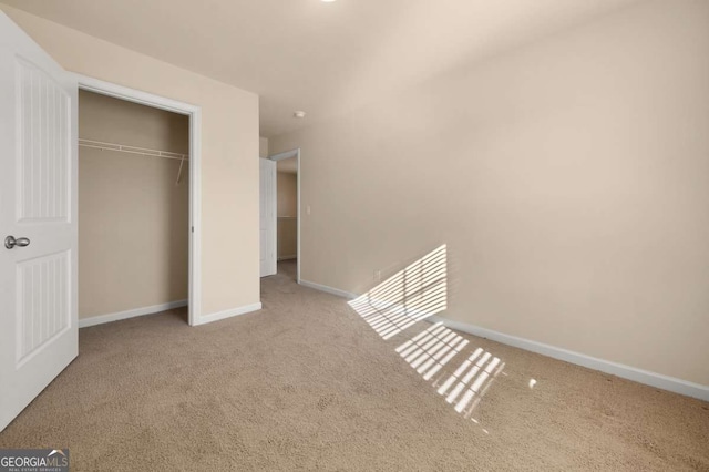 unfurnished bedroom with light colored carpet and a closet