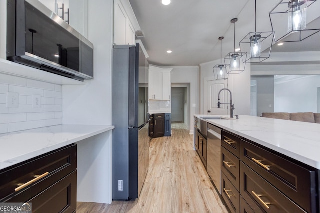 kitchen featuring crown molding, stainless steel appliances, tasteful backsplash, white cabinets, and decorative light fixtures