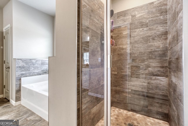 bathroom with shower with separate bathtub and tile walls