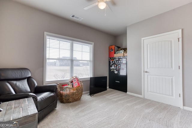 living area with plenty of natural light, light colored carpet, and ceiling fan