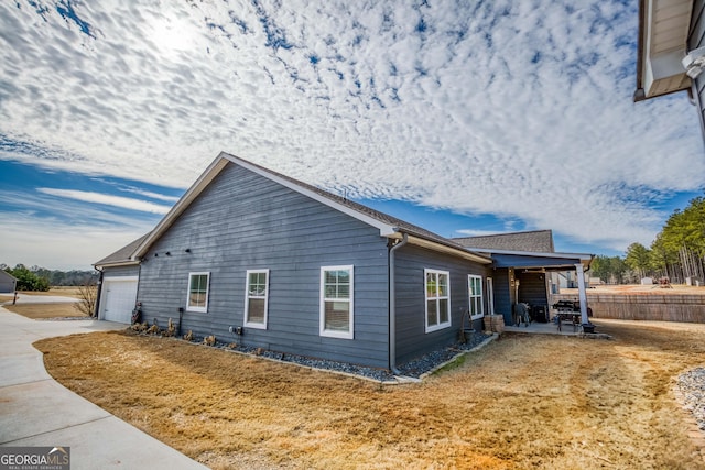 view of side of property with a garage, a lawn, and a patio