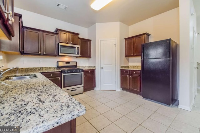 kitchen with appliances with stainless steel finishes, light stone countertops, sink, and light tile patterned floors