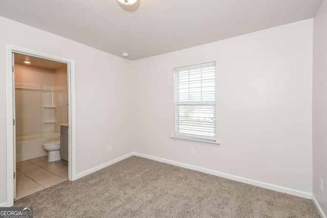 unfurnished bedroom with connected bathroom, a walk in closet, and carpet flooring