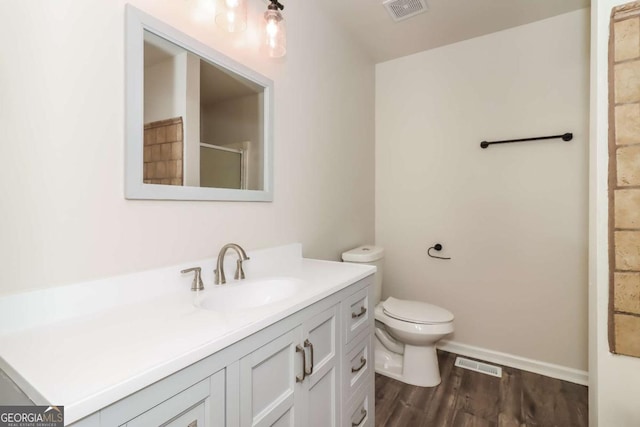 bathroom with an enclosed shower, hardwood / wood-style floors, vanity, and toilet