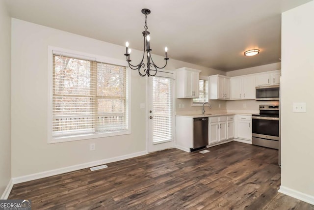 kitchen with white cabinetry, appliances with stainless steel finishes, decorative light fixtures, and sink