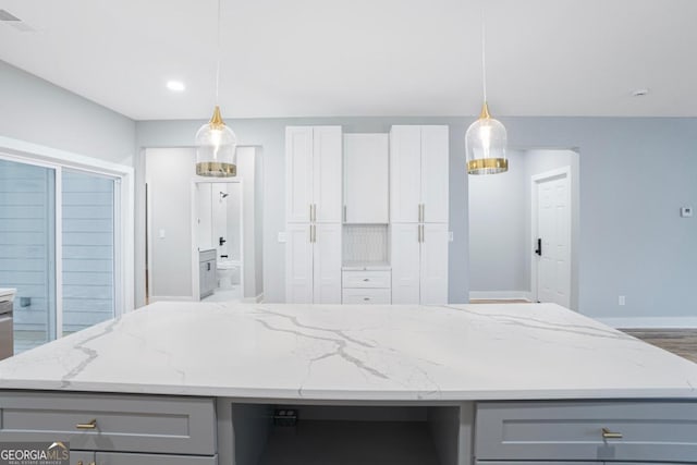 kitchen featuring light stone counters, decorative light fixtures, gray cabinets, and a kitchen island