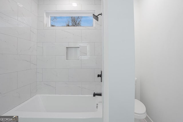 bathroom with tiled shower / bath combo and toilet