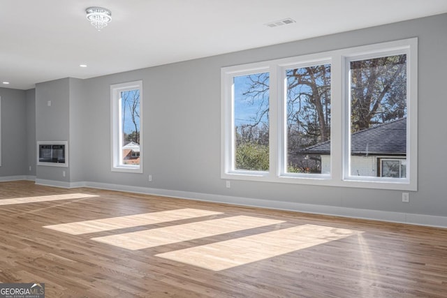 unfurnished living room with a healthy amount of sunlight, heating unit, and light hardwood / wood-style floors