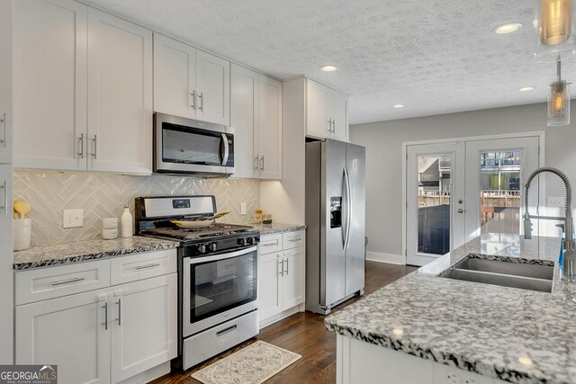 kitchen featuring a kitchen island with sink, light stone countertops, white cabinets, and appliances with stainless steel finishes