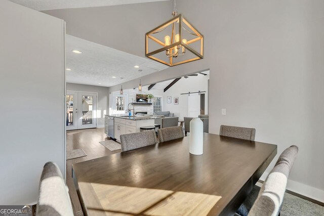 kitchen with appliances with stainless steel finishes, white cabinetry, a breakfast bar area, hanging light fixtures, and a center island with sink