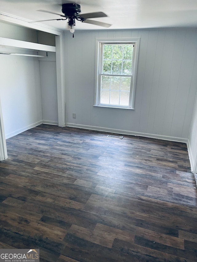 unfurnished bedroom featuring ceiling fan, dark hardwood / wood-style flooring, and a closet