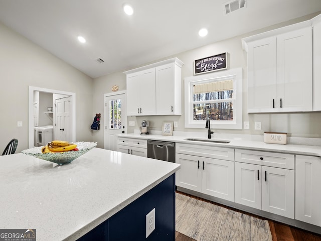 kitchen featuring sink, washer and clothes dryer, dishwasher, white cabinetry, and vaulted ceiling