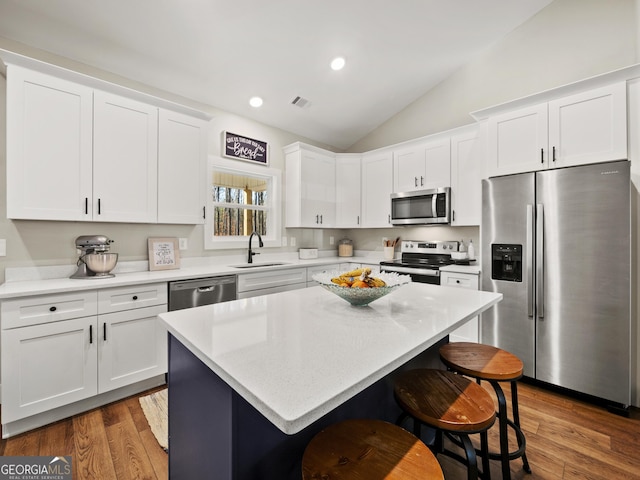 kitchen featuring a kitchen island, sink, white cabinets, a kitchen bar, and stainless steel appliances