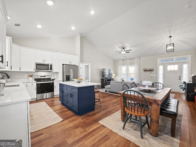 kitchen featuring blue cabinetry, decorative light fixtures, a center island, appliances with stainless steel finishes, and white cabinets