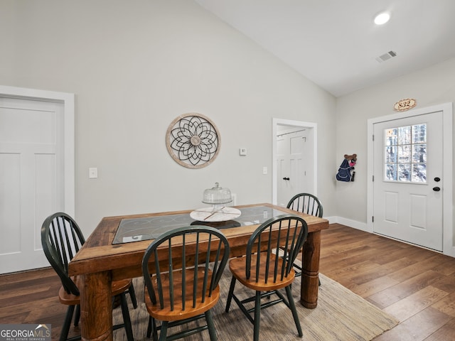 dining room featuring dark wood-type flooring and high vaulted ceiling