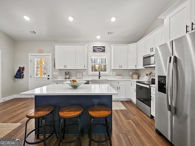 kitchen with sink, a center island, appliances with stainless steel finishes, a wealth of natural light, and white cabinets