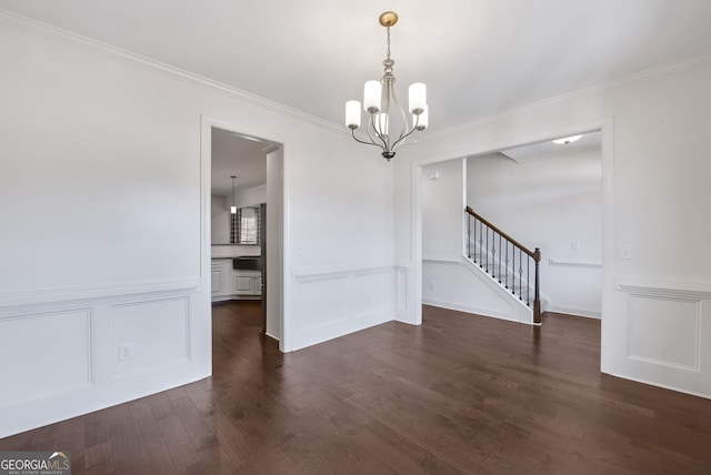 unfurnished dining area featuring dark wood-type flooring, crown molding, and an inviting chandelier