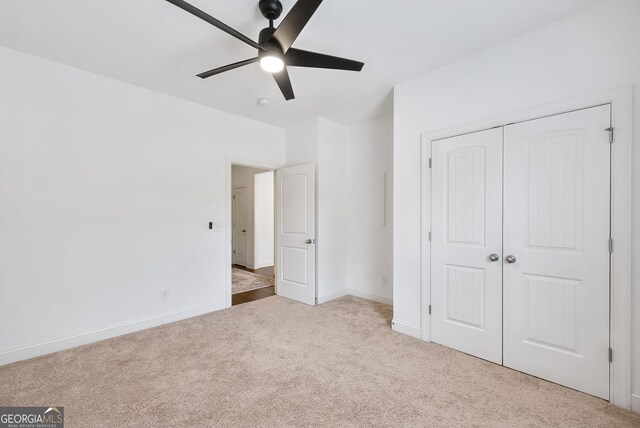 unfurnished bedroom featuring ceiling fan, a closet, and light carpet