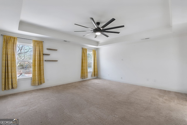 carpeted spare room featuring a raised ceiling and ceiling fan