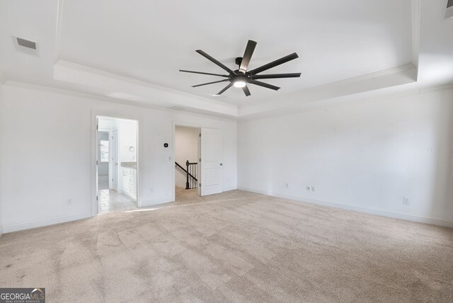 spare room featuring ornamental molding, light colored carpet, ceiling fan, and a tray ceiling