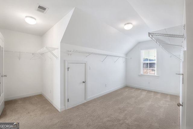 walk in closet with vaulted ceiling and light carpet