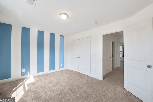 unfurnished bedroom featuring light carpet and a closet