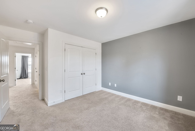 unfurnished bedroom with light carpet and a closet