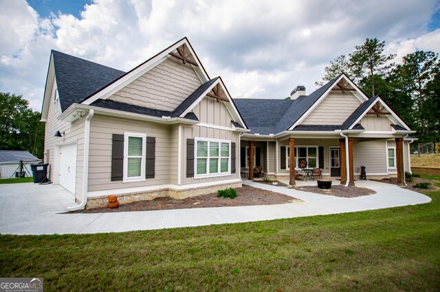 craftsman house with a garage, covered porch, and a front lawn