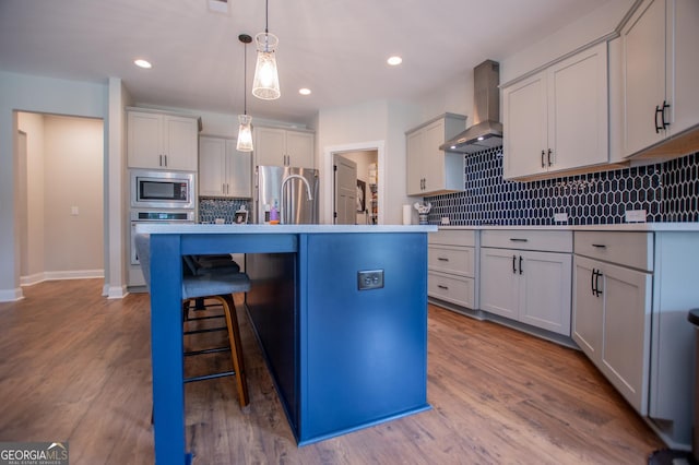 1291 Pleasant Grove Church Rd, Villa Rica, GA 30180 - kitchen featuring pendant lighting, wall chimney range hood, stainless steel appliances, a center island with sink, and light hardwood / wood-style flooring