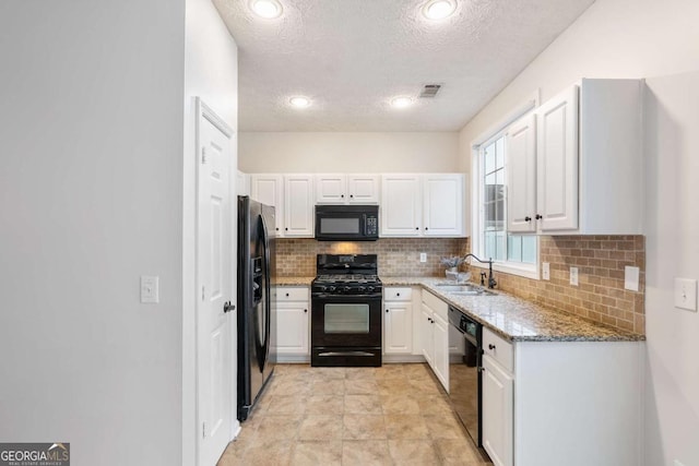 kitchen with sink, tasteful backsplash, black appliances, light stone countertops, and white cabinets