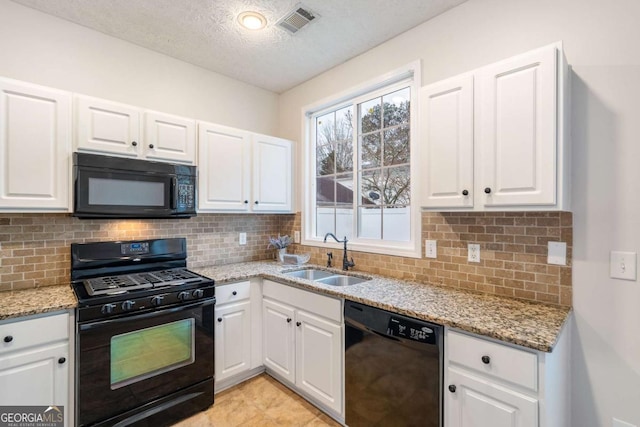 kitchen featuring sink, black appliances, light stone countertops, white cabinets, and decorative backsplash