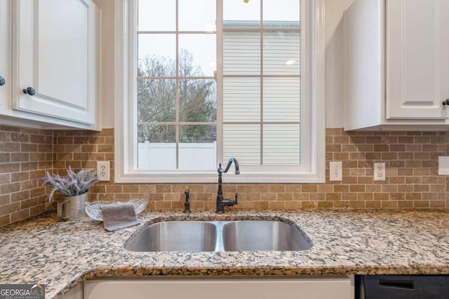 kitchen with white cabinetry, light stone countertops, sink, and decorative backsplash